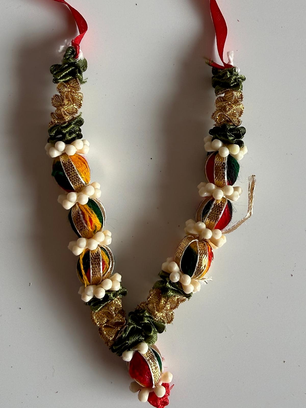 Full view of handcrafted garland with vibrant red, gold, and green