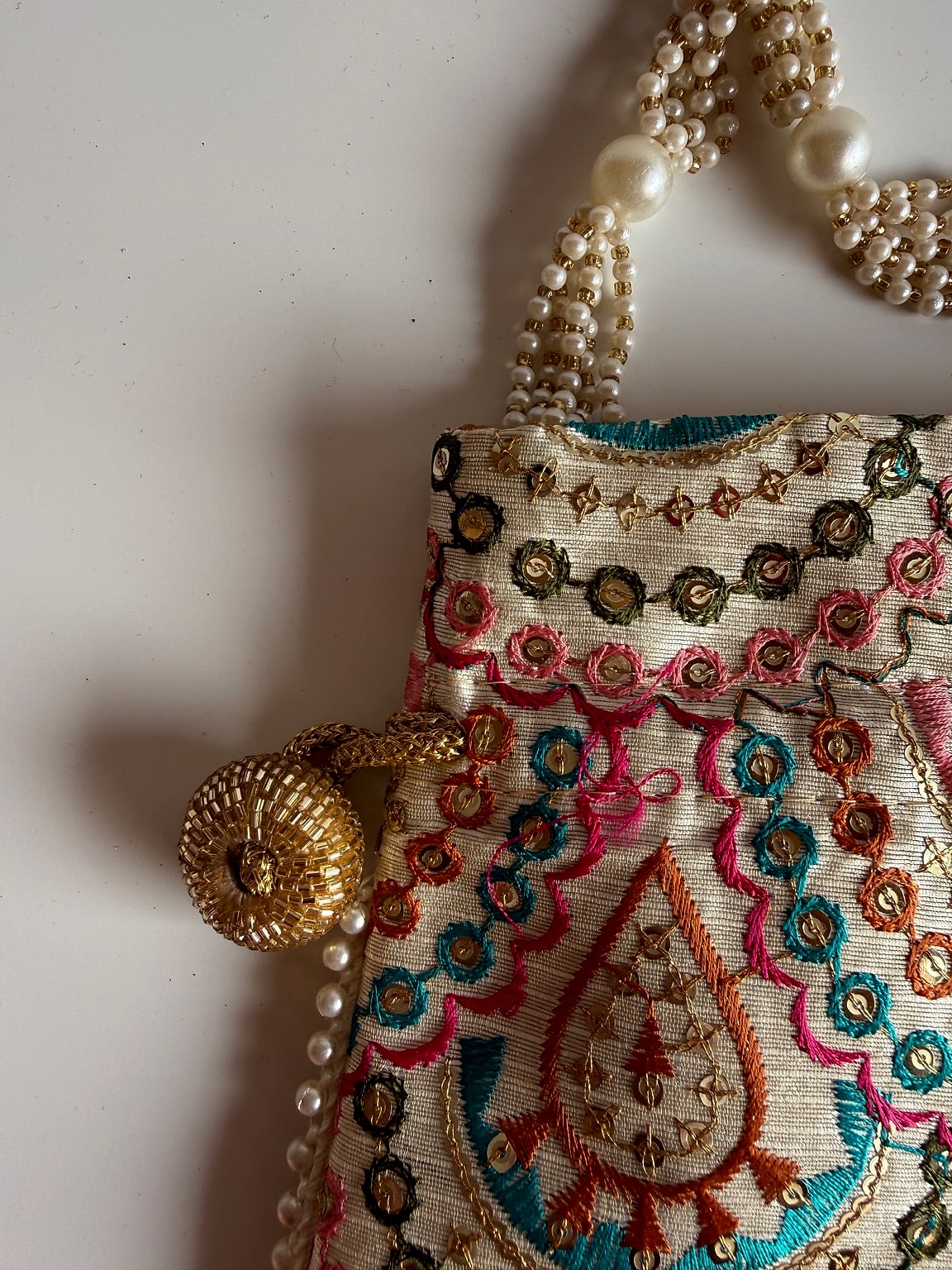 Pearl handle of potli bag with golden drawstring