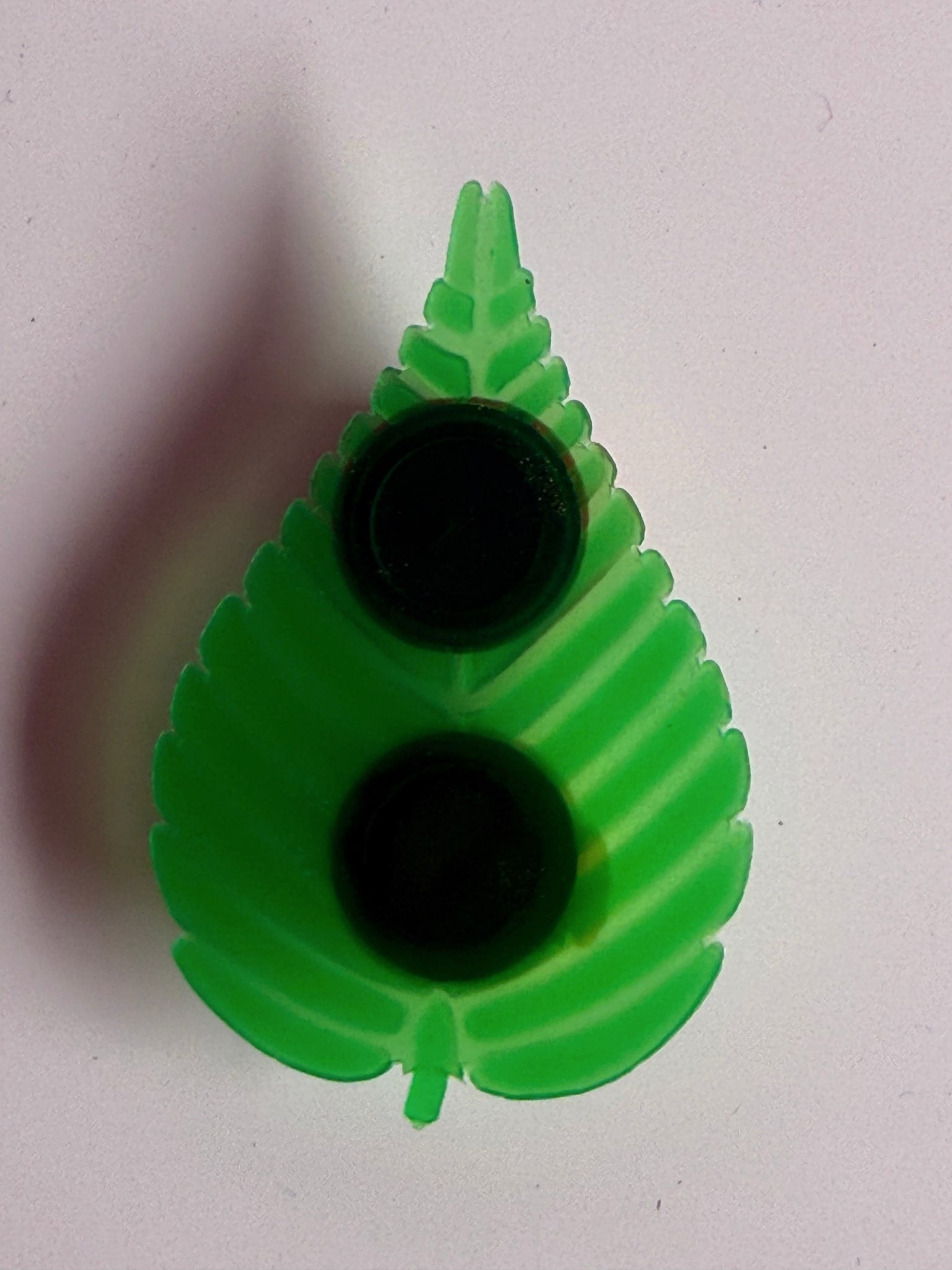 Close-up of green plastic leaf-shaped holder with integrated lids